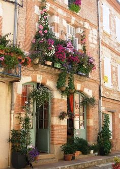 an old building with flowers growing on the windows