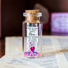 a bottle filled with confetti sitting on top of a table next to an open book