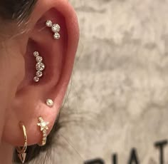 a woman wearing three different types of ear piercings