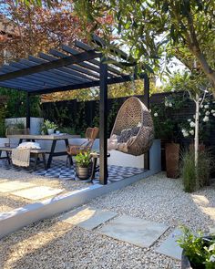 an outdoor dining area with chairs and tables under a pergolated roof, surrounded by gravel