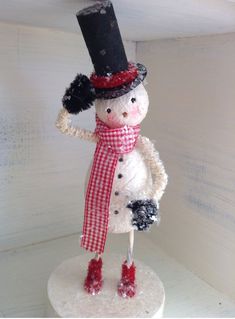 a snowman with a hat and scarf standing on top of a white shelf in the corner