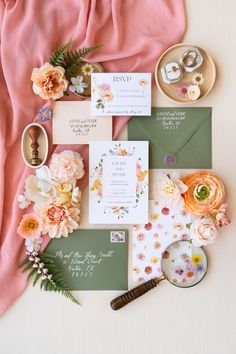 the wedding stationery is laid out on top of each other with flowers and greenery