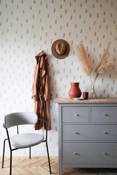 a room with a dresser, chair and coat rack