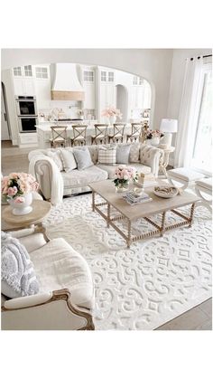 a living room filled with lots of furniture and flowers on top of a white rug