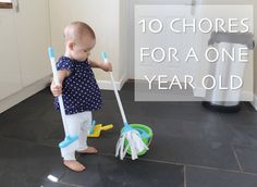 a baby standing on the floor holding two toothbrushes