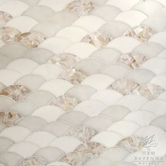 a close up view of a white and beige mosaic tile wall with wavy, scallop - like shapes