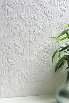 a potted plant sitting on top of a white shelf next to a wallpaper