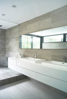 a modern bathroom with two sinks and large mirrors