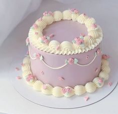 a pink cake with white frosting and flowers on top