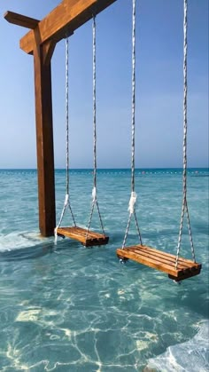 two wooden swings suspended over the ocean water