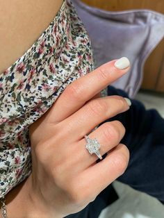 a woman's hand with a diamond ring on her left finger and white nail polish