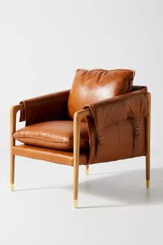 a brown leather chair sitting on top of a white floor next to a wooden frame