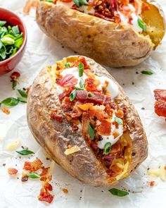 two baked potatoes with bacon, cheese and spinach sprinkled on the side