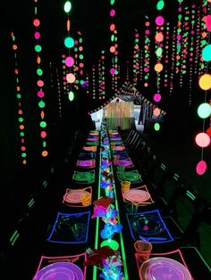 a long table is lit up with colorful lights and plates on the tables in front of it