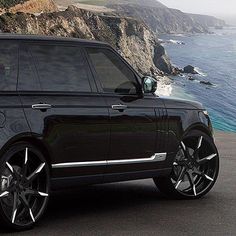 a black range rover parked in front of the ocean