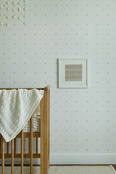 a baby crib with a blanket on top of it next to a white wall