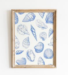 a blue and white wall hanging with seashells on it's side in a wooden frame