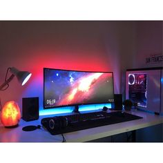 a desk with a computer monitor and speakers on it, next to an orange light