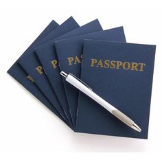 four passport books with a pen resting on one of them and the words passport book written in gold