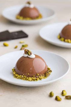 three desserts on white plates with chocolate and pistachio