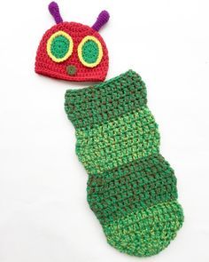 a crocheted caterpillar and a knitted hat on a white surface