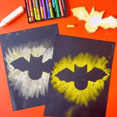 two bats are drawn on black paper with colored crayons next to each other