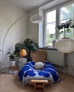 a living room filled with lots of plants next to a large white lamp and window