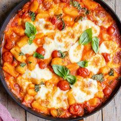 a pan filled with pasta and sauce on top of a wooden table