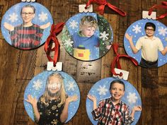 four ornament shaped like children's faces on a wooden table with red ribbon