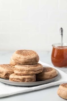 a stack of cookies sitting on top of a white plate next to a jar of peanut butter