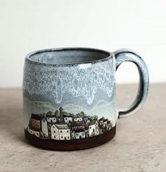 a ceramic mug with houses painted on the outside and inside is sitting on a table