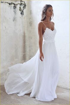 a woman wearing a white dress standing in front of a wall