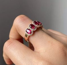 a woman's hand holding an engagement ring with three oval shaped ruby stones on it