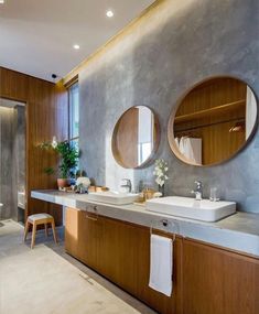 a bathroom with two round mirrors above the sinks and wooden cabinetry on the wall