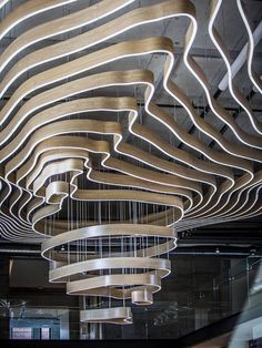 the suspended light fixture is made out of wood and has curved wooden strips hanging from it