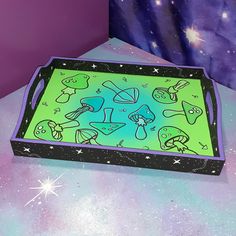 a green and black tray with cartoon drawings on the bottom is sitting on a table