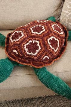 a crocheted turtle pillow sitting on top of a couch next to a pillow