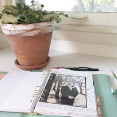 a potted plant sitting on top of a desk next to an open notebook and pen