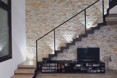 a television sitting on top of a wooden shelf under a stair case