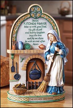 a statue of a woman holding a broom in front of a kitchen stove with the words irish kitchen prayer written on it