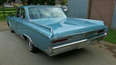 an old blue car is parked on the street