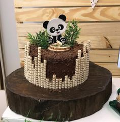 a panda bear cake sitting on top of a wooden table next to a green plant