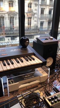 an electronic keyboard sitting on top of a glass table next to a speaker and other electronics