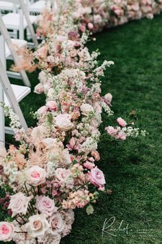 the aisle is lined with flowers and white chairs