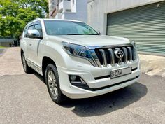 a white toyota land cruiser parked in front of a garage