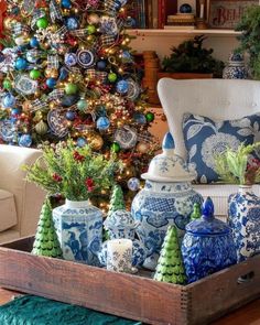 a christmas tree is decorated with blue and white ornaments in front of a living room couch