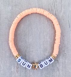 SUN BUM Bracelet ☀️🌴 This bracelet is for the lover of the sun, with a drink in her hand and her feet in the sand ☀️☀️ Made with peach mini heishi beads, 18k gold filled accents and mini square letters that read "SUN BUM" If you would like another word or color, please put in Personalization Section* CARING TIPS FOR YOUR JEWELRY ⭐️Treat and store with care. ⭐️ For longevity, avoid exposing your jewelry to water. ⭐️ Avoid having direct contact with lotions, perfumes, sanitizers as these chemical Call Bead Bracelets, Personalized Gold Friendship Bracelets For Beach, Adjustable Gold Stretch Bracelet For Vacation, Beach Bracelet With Letter Beads, Adjustable Stretch Bracelet With Letter Beads For Vacation, Adjustable Letter Beads Stretch Bracelet For Vacation, Personalized Bohemian Friendship Bracelets For Beach, Summer Letter Bead Strand Bracelets, Summer Letter Beads Strand Bracelet