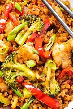 a bowl filled with rice, broccoli and other vegetables next to chopsticks