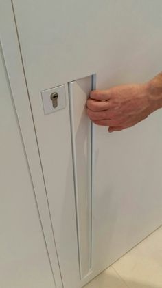 a person's hand is holding the door handle on a white refrigerator freezer