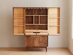 a wooden cabinet sitting in the corner of a room with white walls and flooring